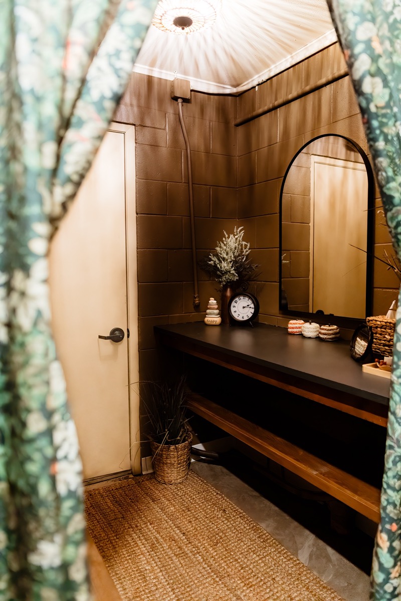 Homey changing area with wooden vanity, mirror, and floral curtains