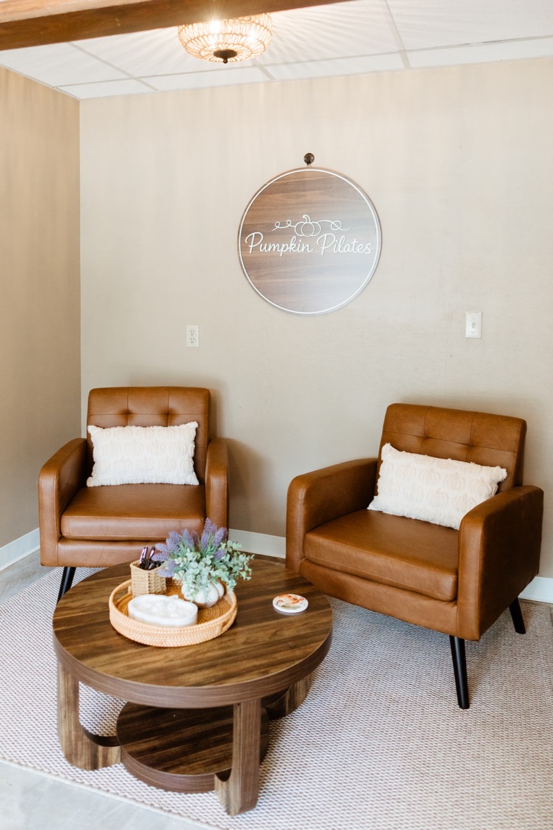 Cozy waiting lounge with leather chairs and the Pumpkin Pilates wall sign